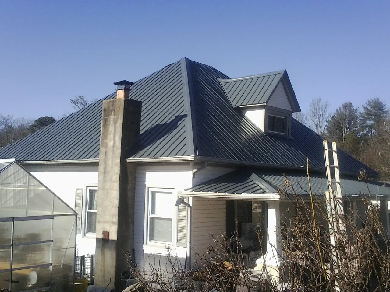 Dark blue standing seam metal roof on a white farmhouse with dormer — Slate & Tile Roof Repair by Roofing Brothers in Albert