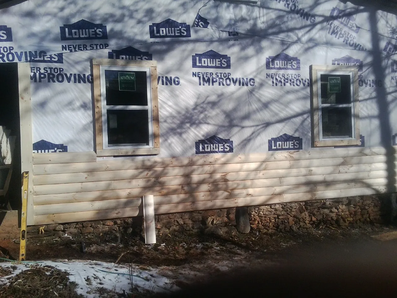 House wrap and new log siding going up on an exterior wall in Albert