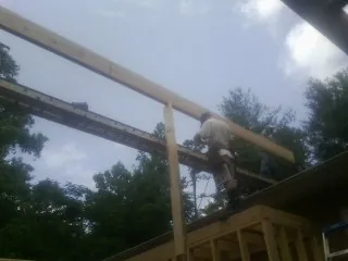 Carpenter setting a ridge beam over a new addition frame — Ice Dam Removal by Roofing Brothers in Albert