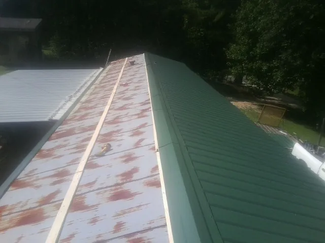 Old rusted panels beside newly installed green metal roofing — Wind Damage Roof Repair by Roofing Brothers in Albert