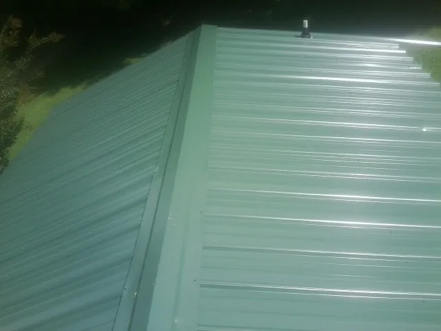 New green metal panels meeting at the ridge of a roof — Flat Roof Repair work by our crew in Albert