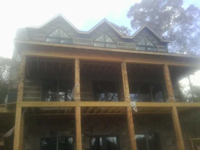 Dormers and porch framing on a large log home under construction — Roof Coating work by our crew in Albert