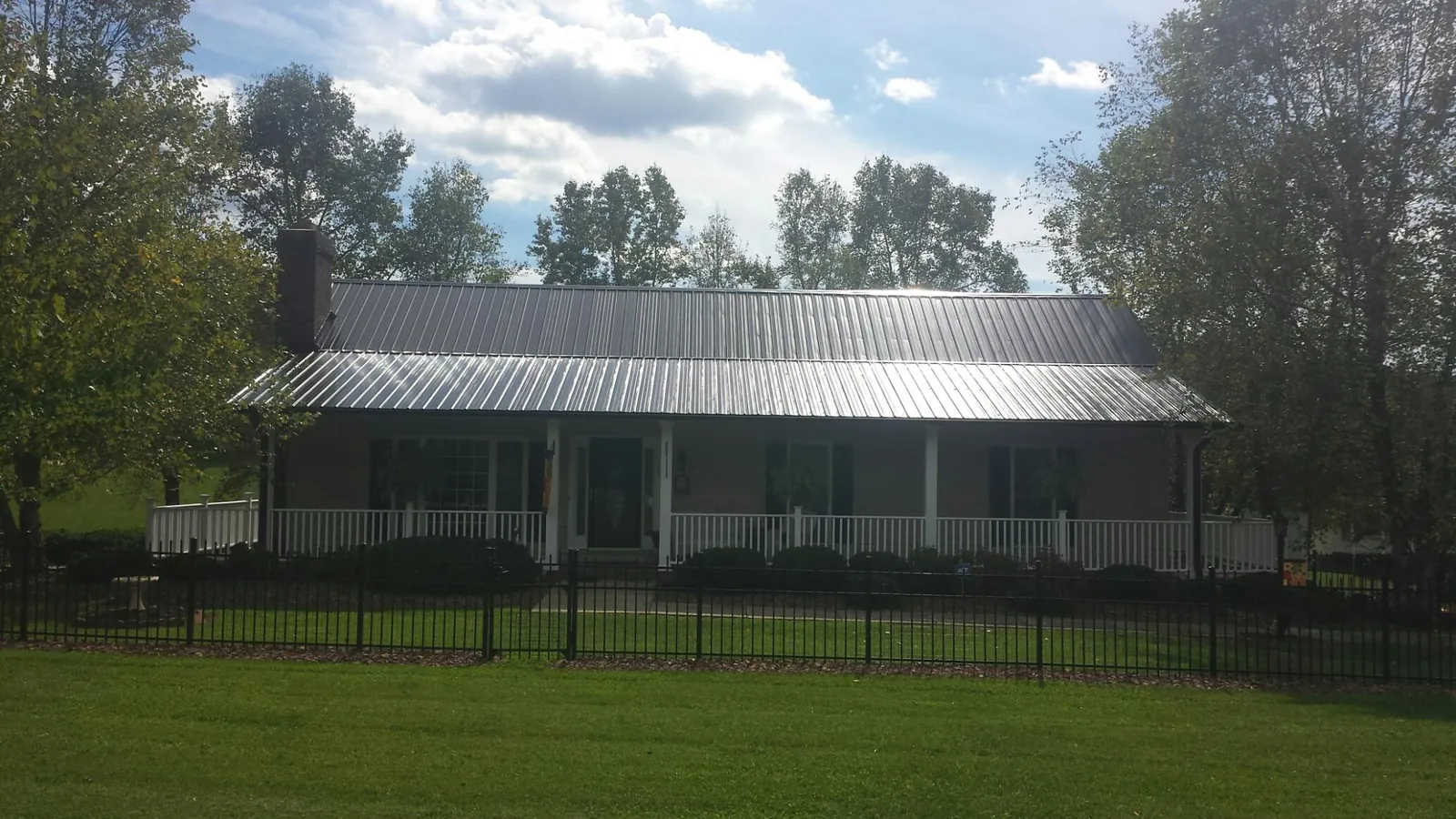 Gray metal roof on a brick ranch with a full width front porch — Gutter Guard Installation work by our crew in Albert